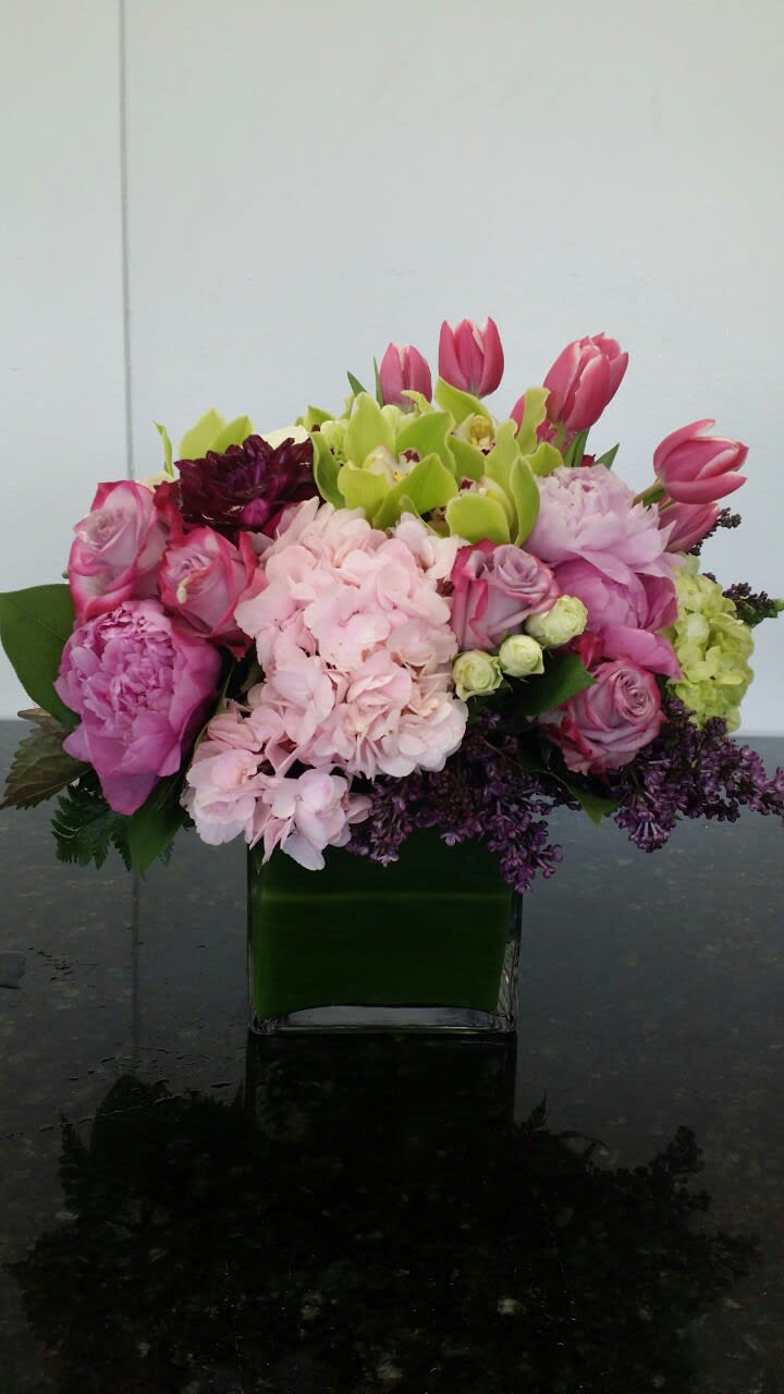 Pink and green mixed flower arrangement in a square glass vase