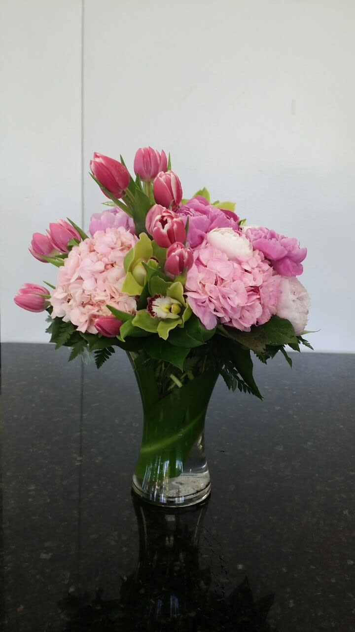 Pink tulips and hydrangeas arranged in a clear glass vase