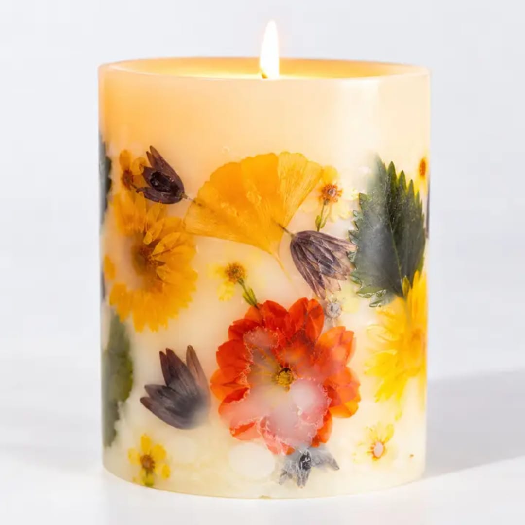 Decorative pillar candle with pressed flowers embedded in wax