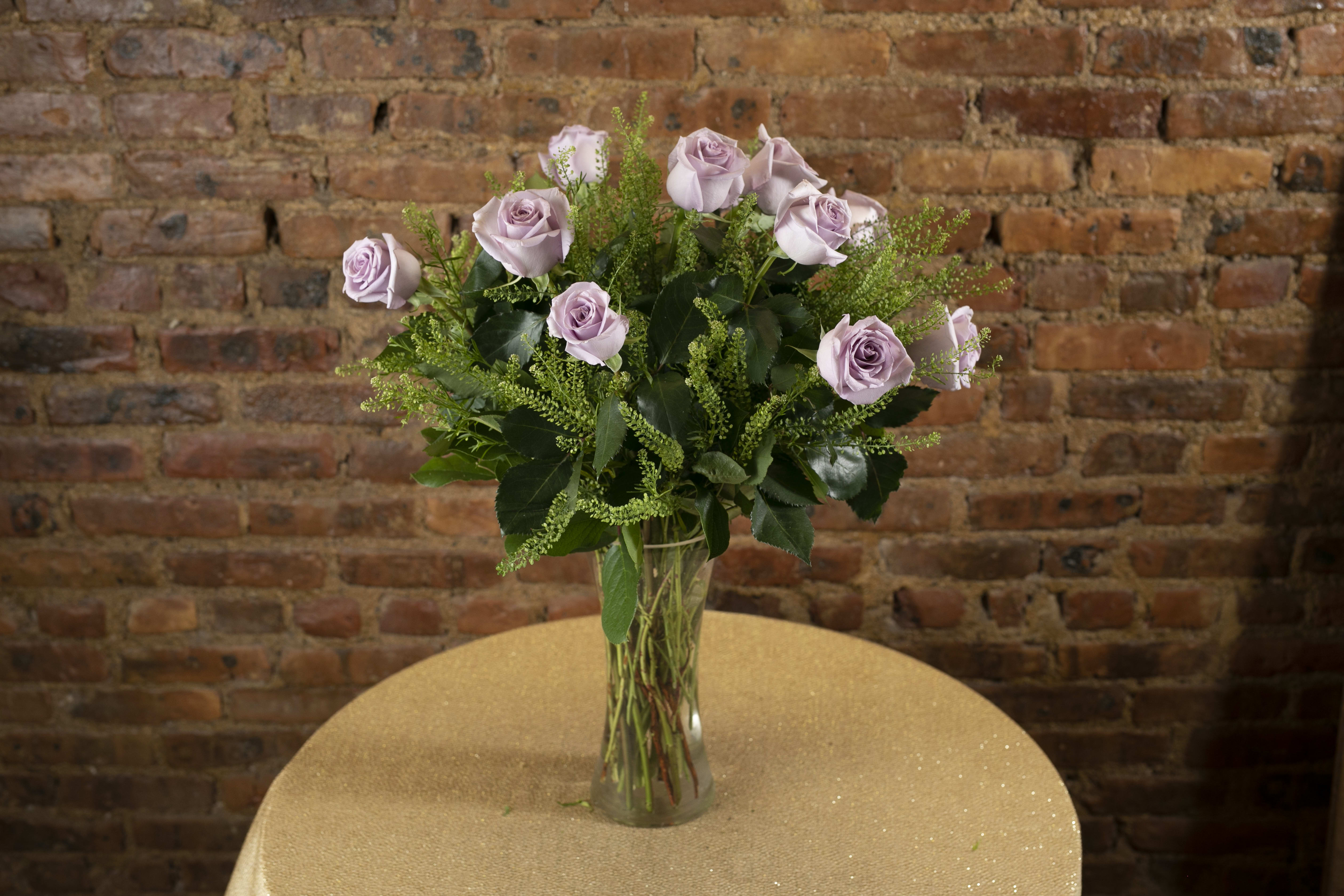 Lavender roses arranged in a clear glass vase