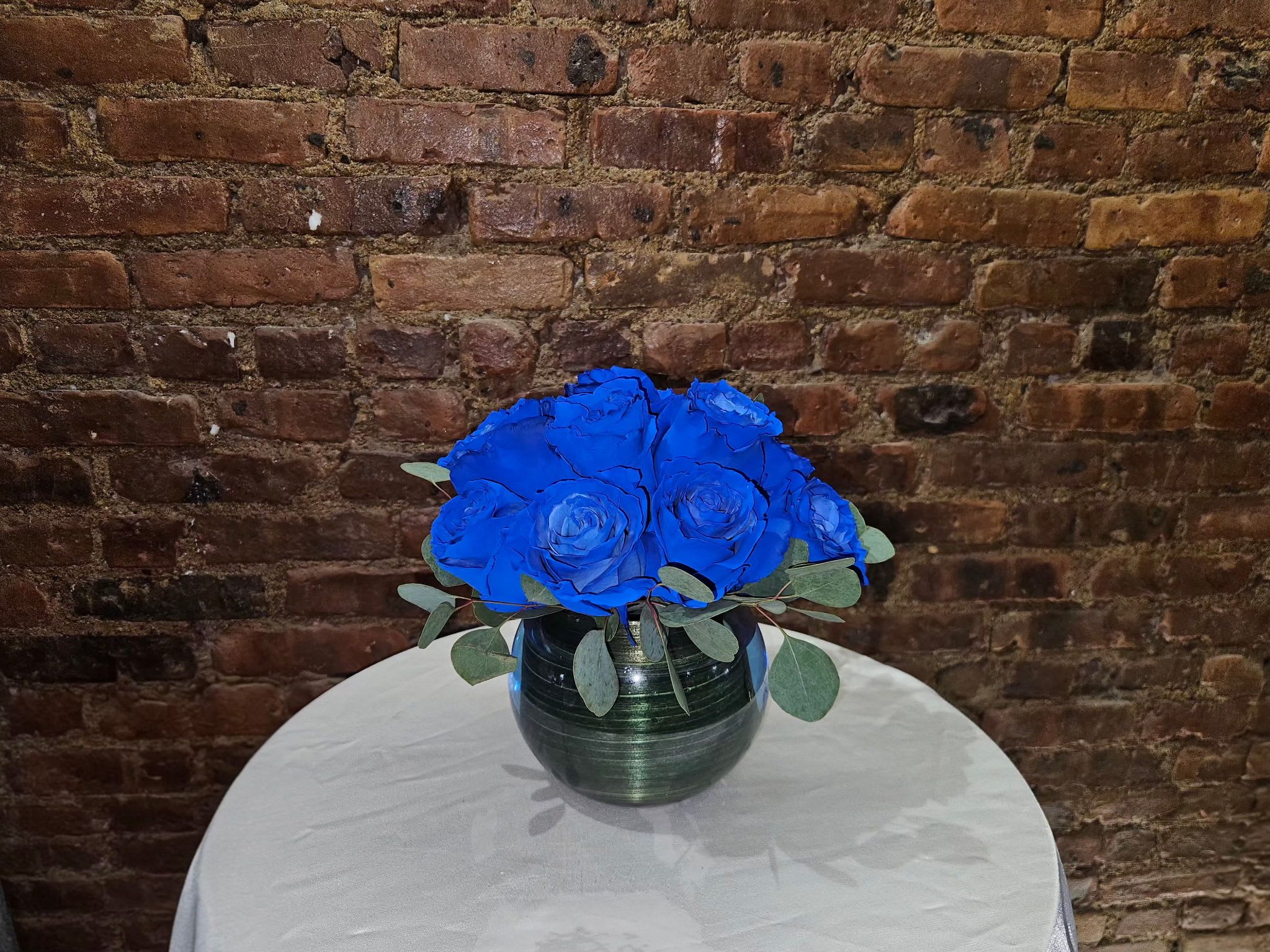 Blue rose bouquet in a dark glass vase on a round table