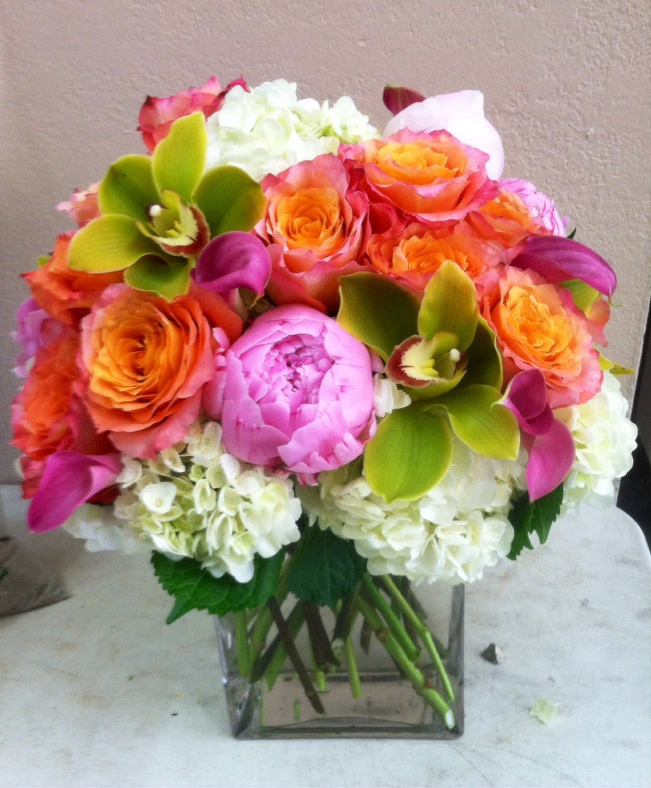 Bouquet of orange and pink roses with white hydrangeas in a glass vase