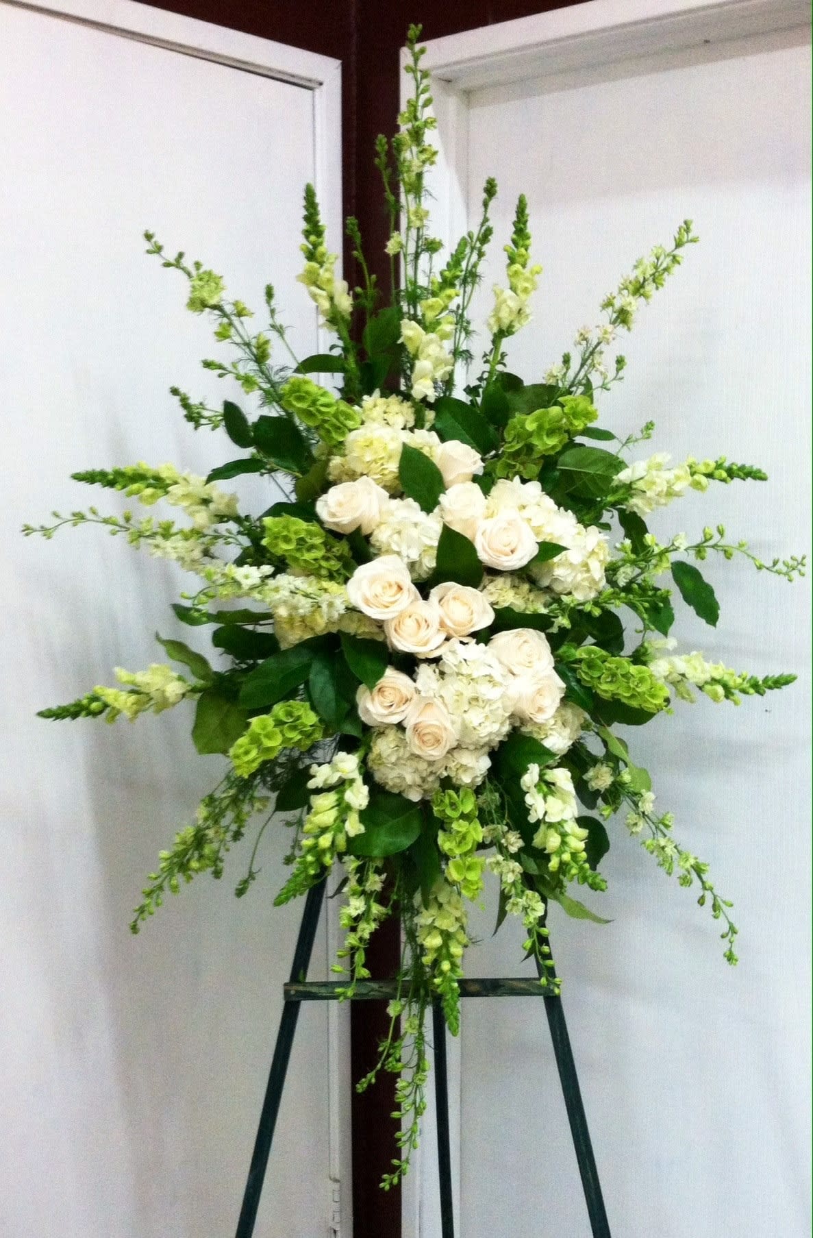 Tall white and green floral standing arrangement on an easel