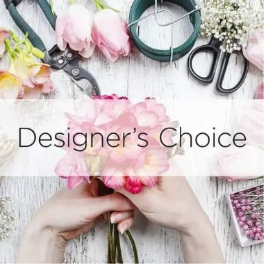 Hands arranging pink flowers with floral tools on a white table