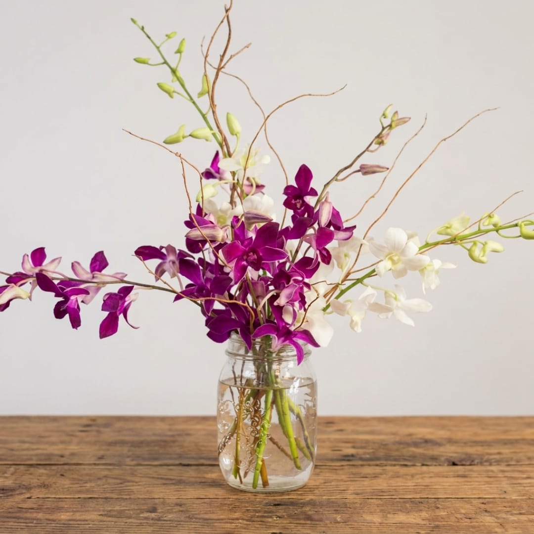 Purple and white orchids in a clear glass jar vase