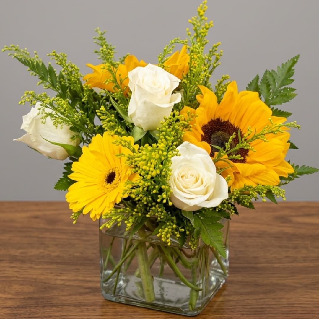 Yellow gerbera daisies and white roses in a square glass vase