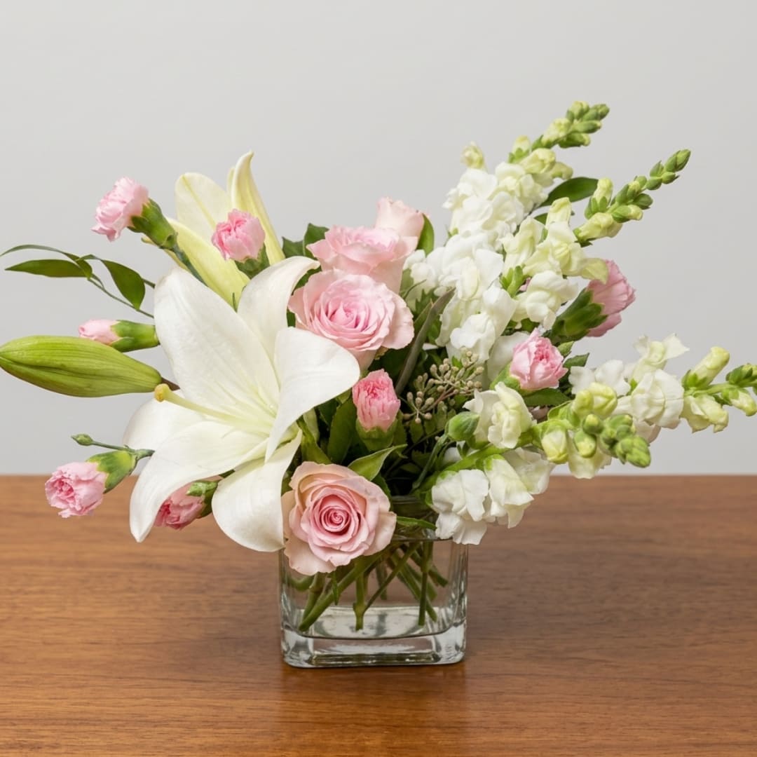 Pink roses and white lilies arranged in a clear glass vase