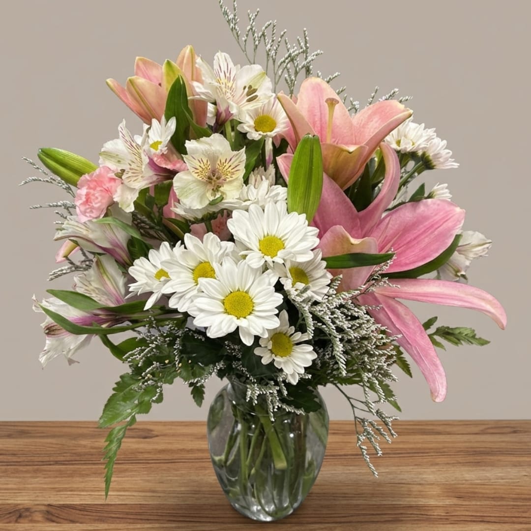 Pink lilies and white daisies in a clear glass vase