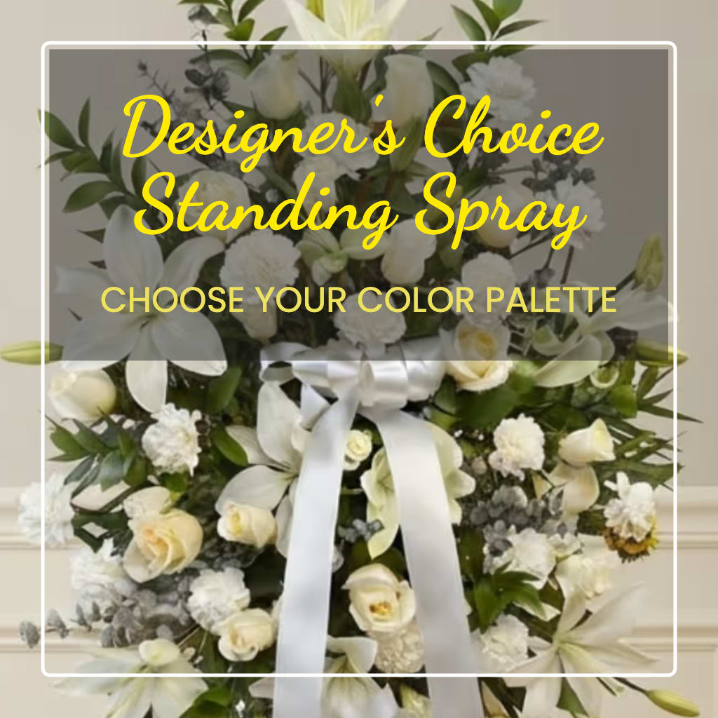 White standing spray with lilies, roses, and carnations tied with a white ribbon