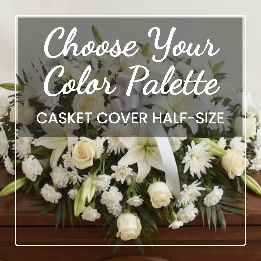 White floral casket cover with lilies, roses, and ribbon