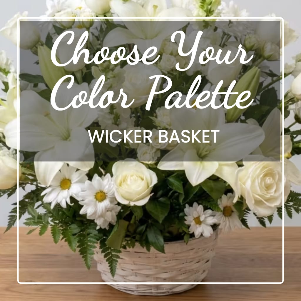 White floral arrangement in a wicker basket with lilies, roses, and daisies