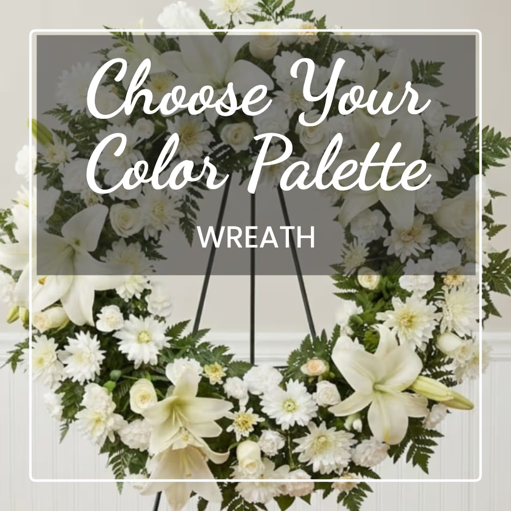 White floral wreath on a stand with lilies and daisies