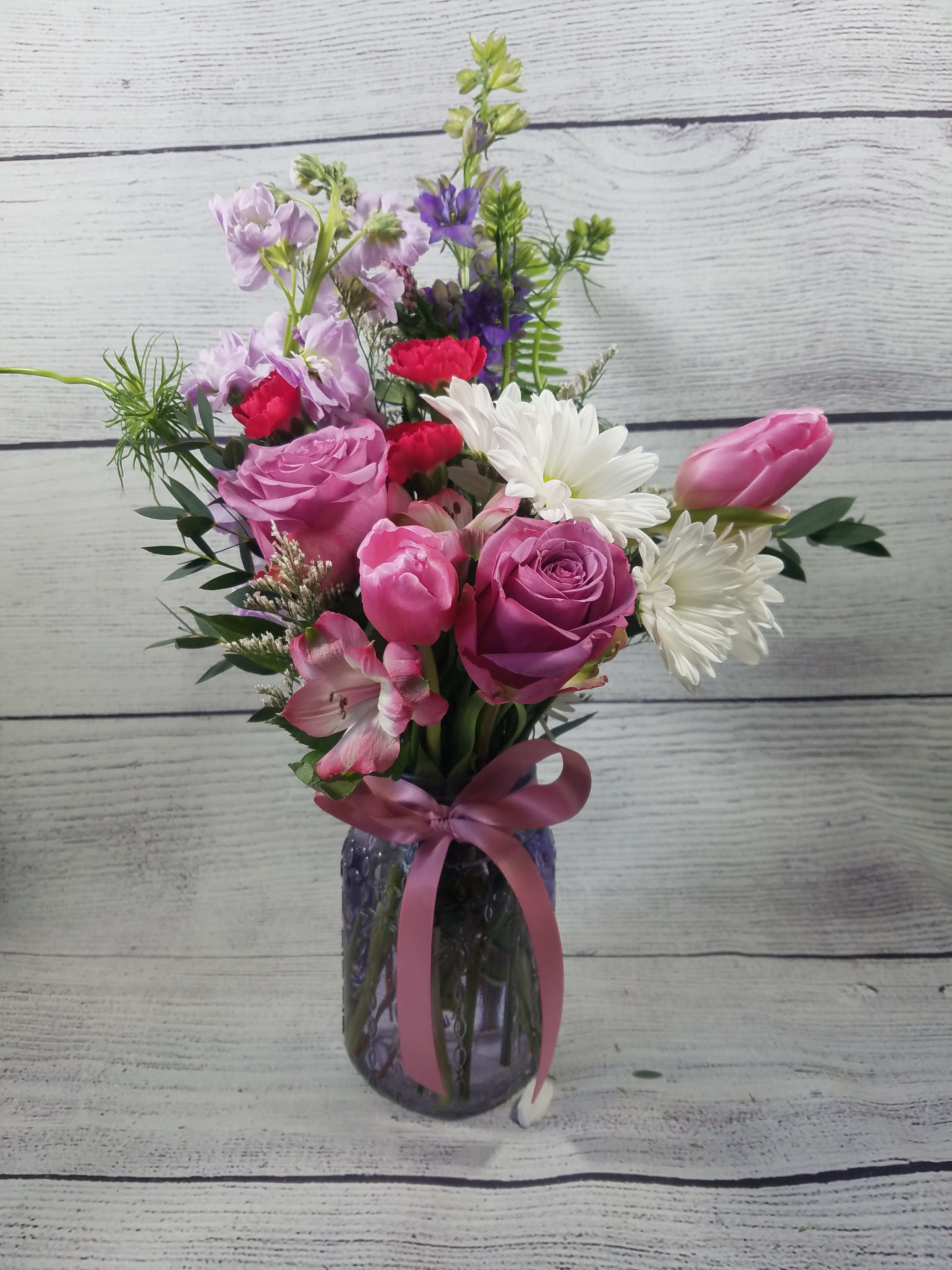 Pink and white mixed bouquet in a glass vase with a ribbon