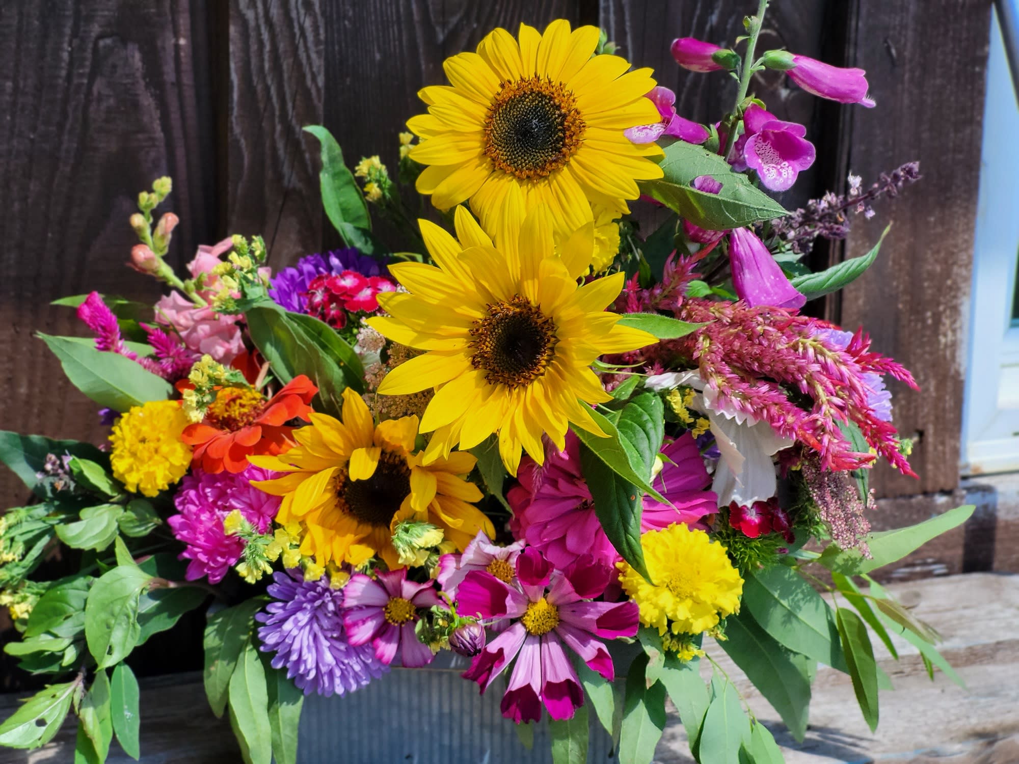 Mixed bouquet with sunflowers and colorful blooms in a metal container