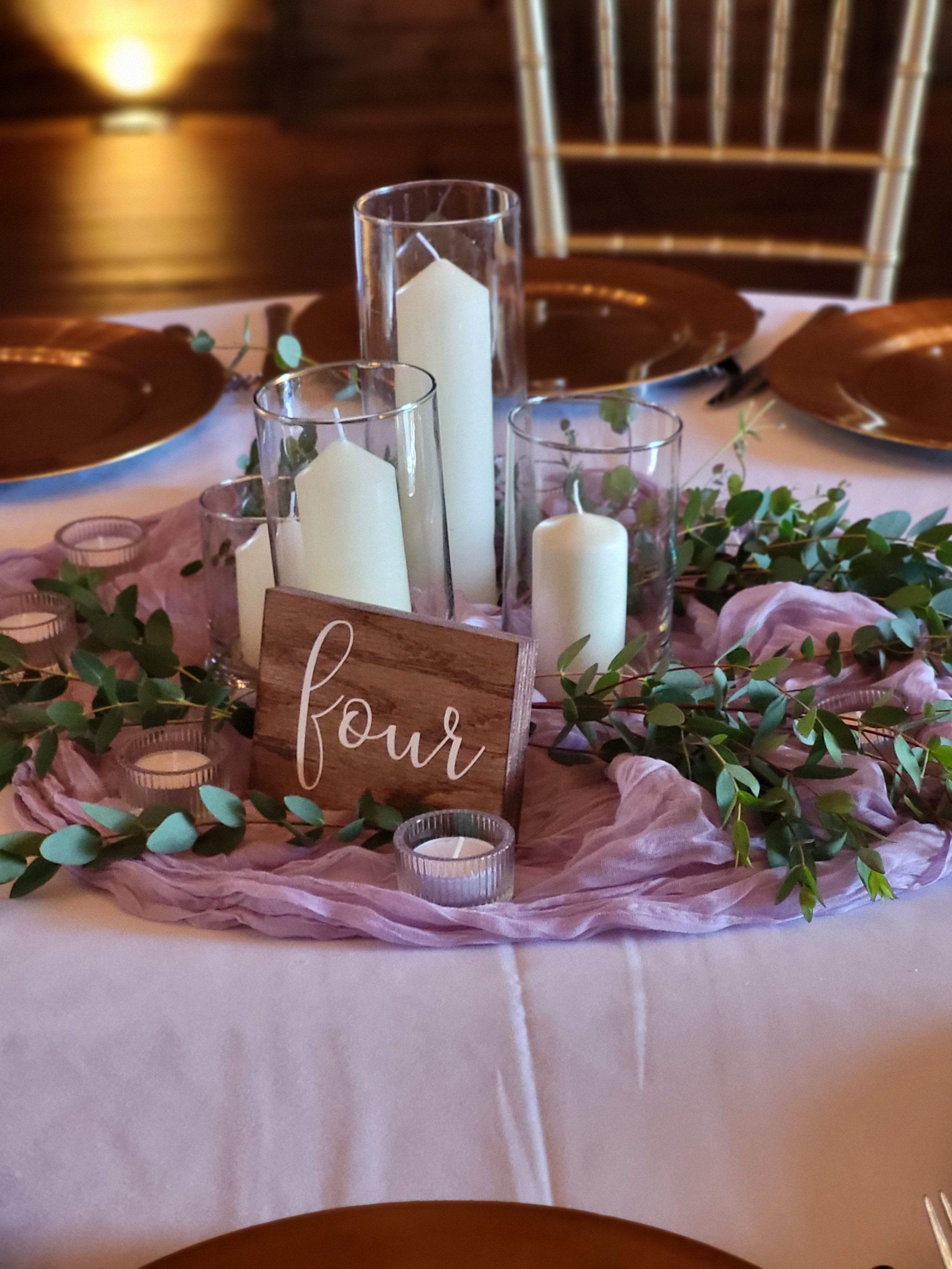 Table centerpiece with candles, greenery, and a wooden sign