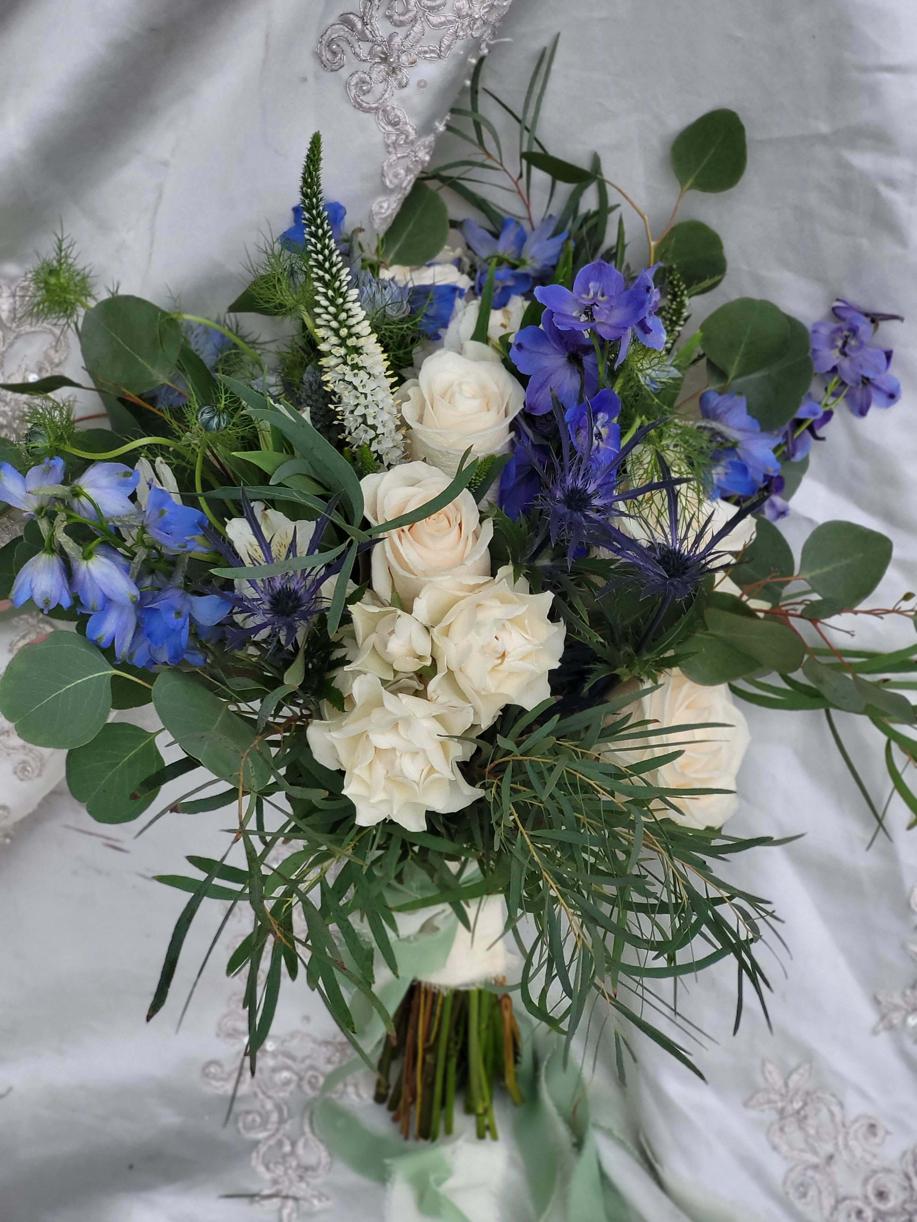Bouquet of white roses and blue flowers with greenery