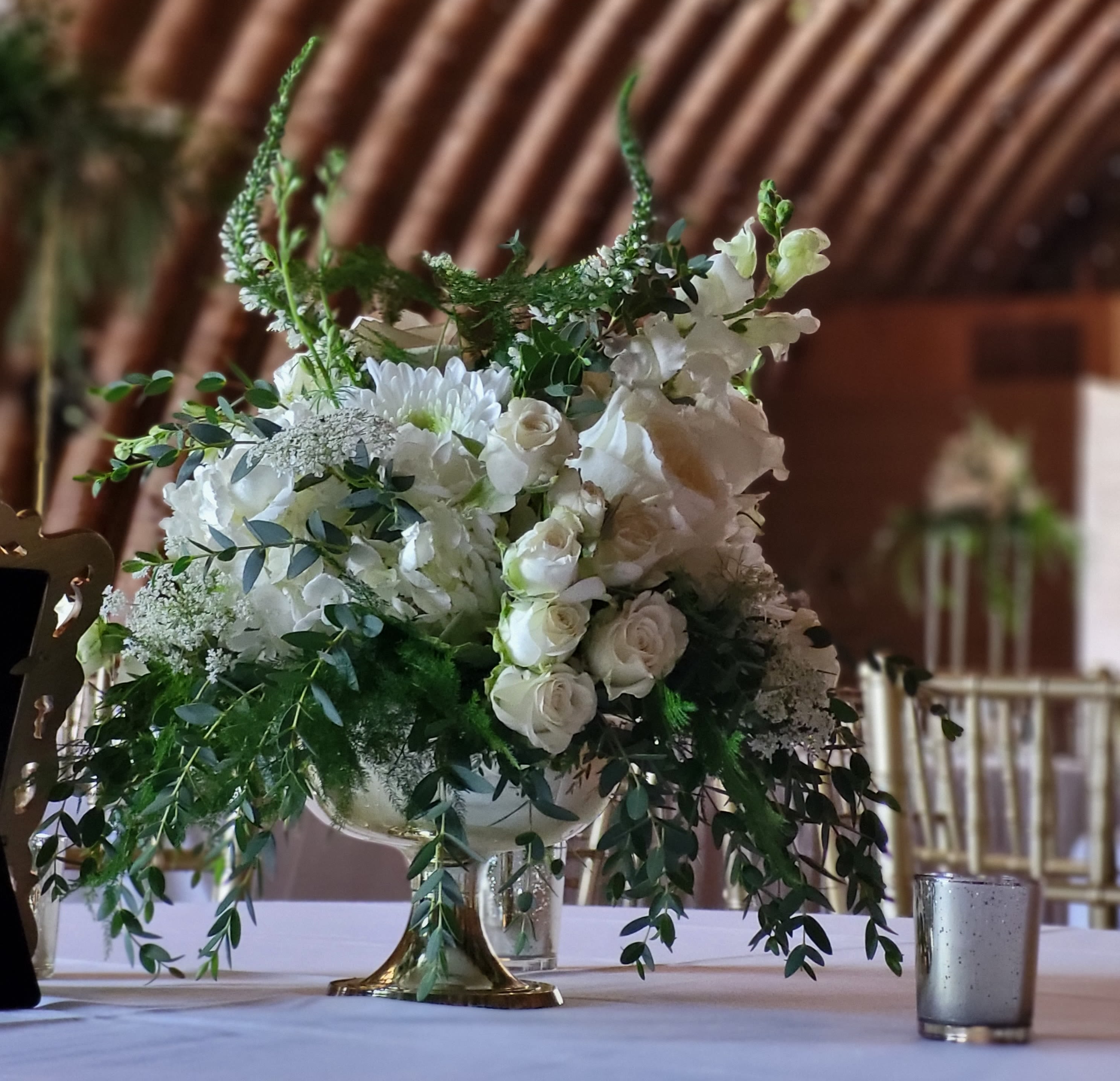 White floral centerpiece in a gold pedestal vase
