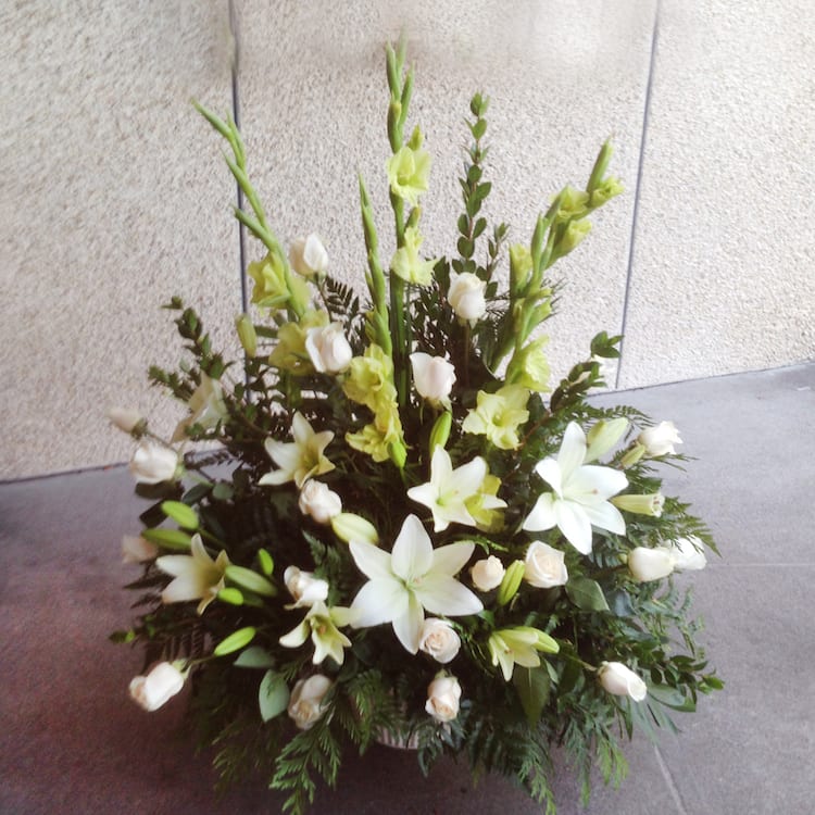 White lilies and pale green gladiolus in a low floral arrangement