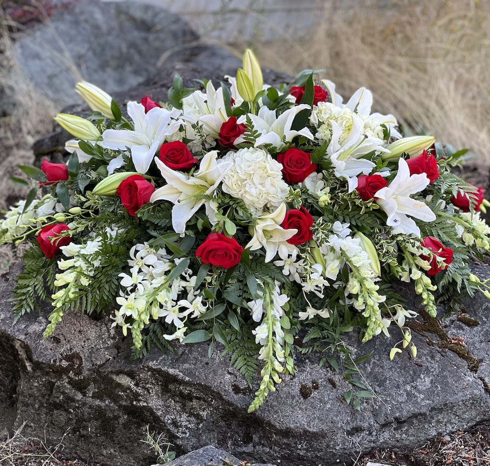 Casket spray of white lilies, red roses, and white orchids