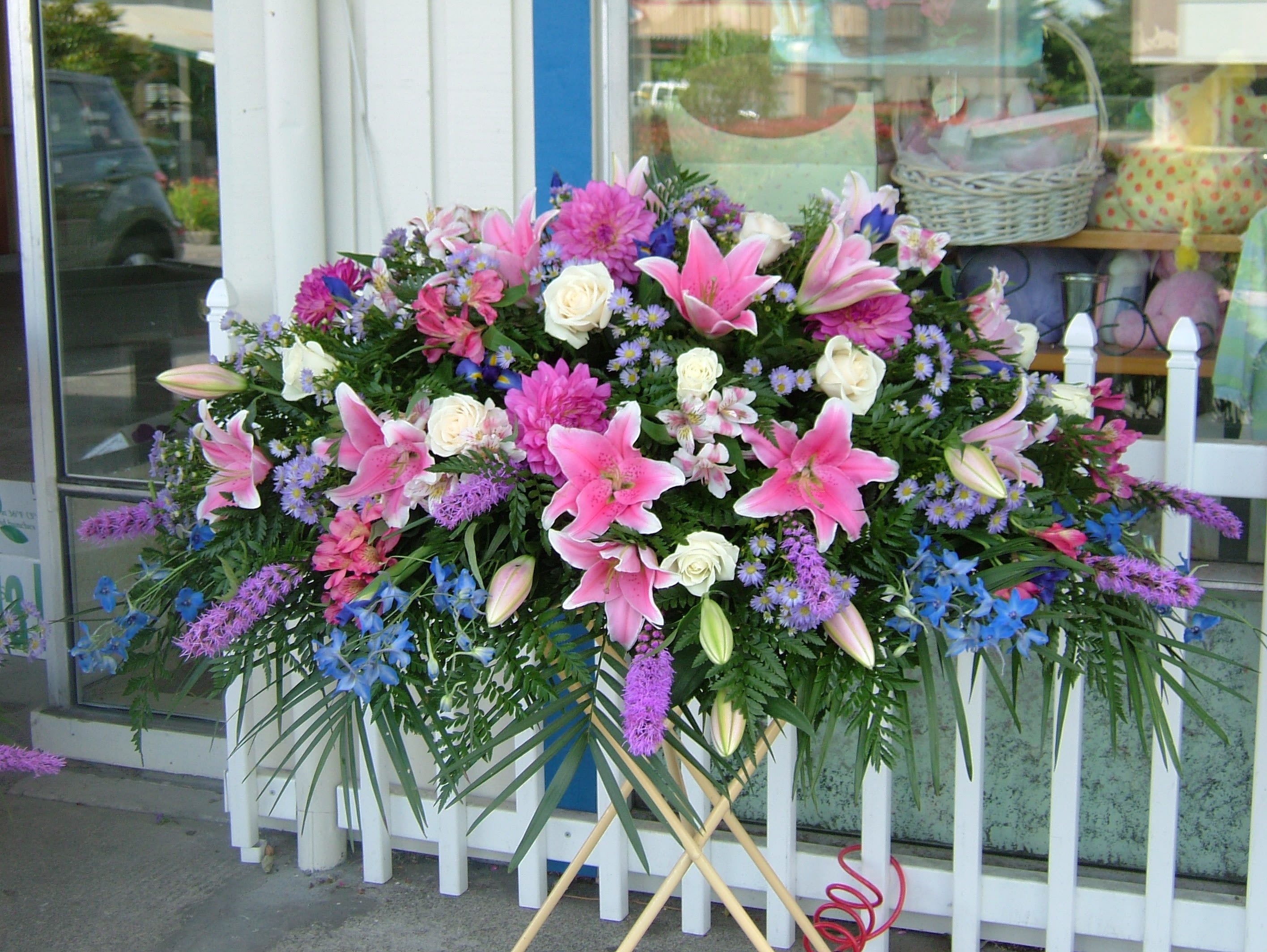 Large standing spray of pink lilies, white roses, and purple flowers