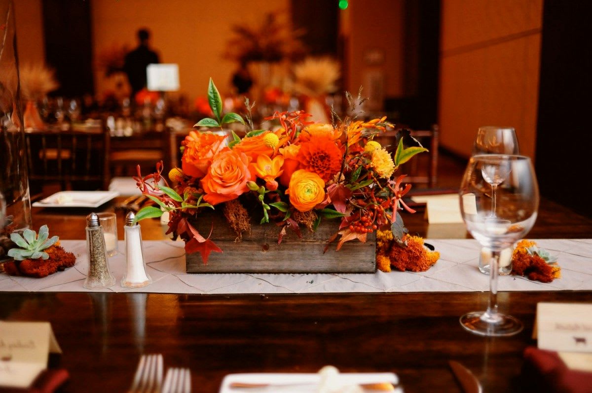 Orange floral centerpiece in a wooden box on a banquet table