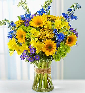 Bouquet of yellow and blue flowers in a clear glass vase