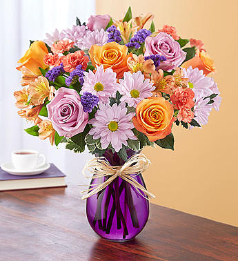 Mixed bouquet of roses, daisies, and alstroemeria in a purple vase