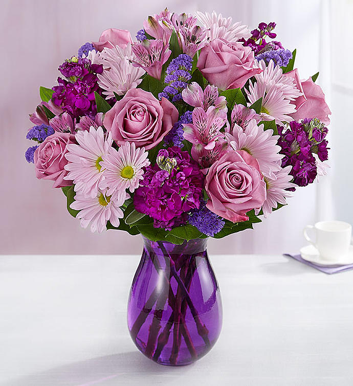 Mom's Lavender Dream  - Here’s a delightful surprise we’ve dreamed up just for your Mom. Our expert florists gathered lavender &amp; purple blooms with lush greenery, creating a lovely contrast of color. It’s all designed inside our striking violet purple vase to capture its rich beauty, along with the thoughtfulness of your sentiment.