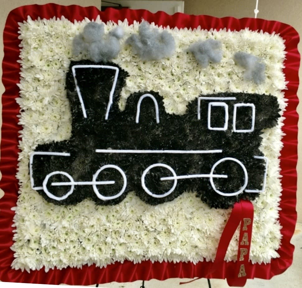 Floral tribute shaped like a train with a red ribbon border