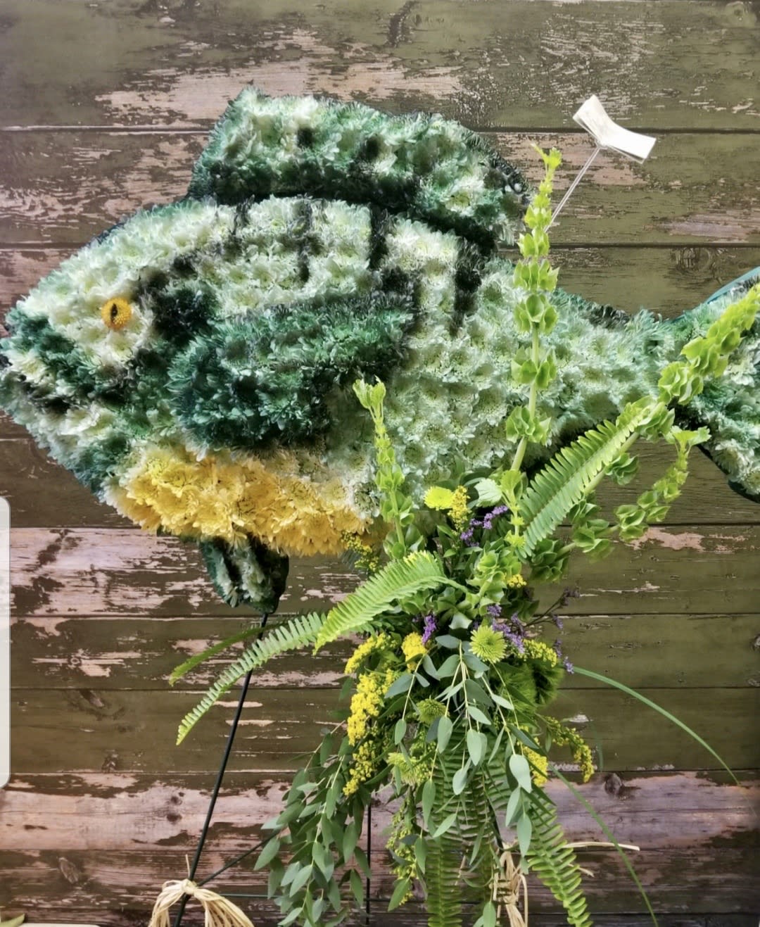 Large fish-shaped floral display with green, white, and yellow flowers