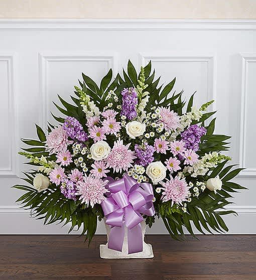 Lavender and white floral arrangement with a purple ribbon in a white vase