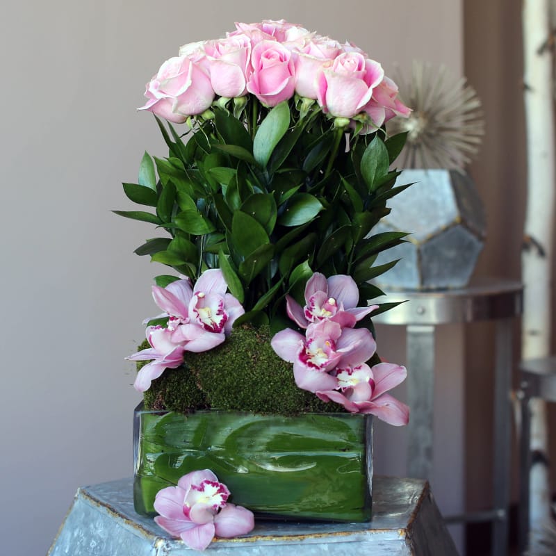 Pink roses and orchids arranged in a glass vase