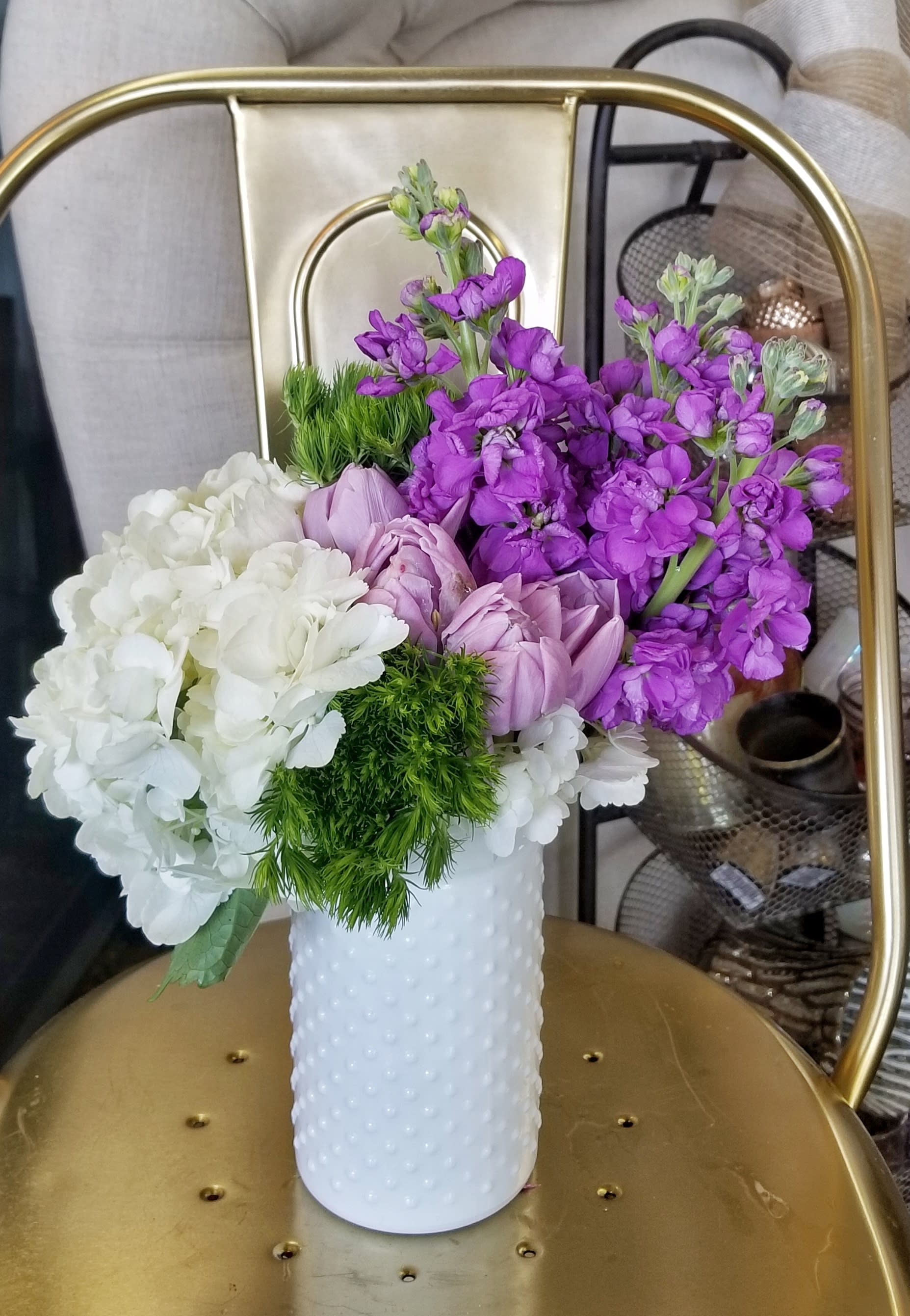 Purple and white flowers arranged in a white textured vase