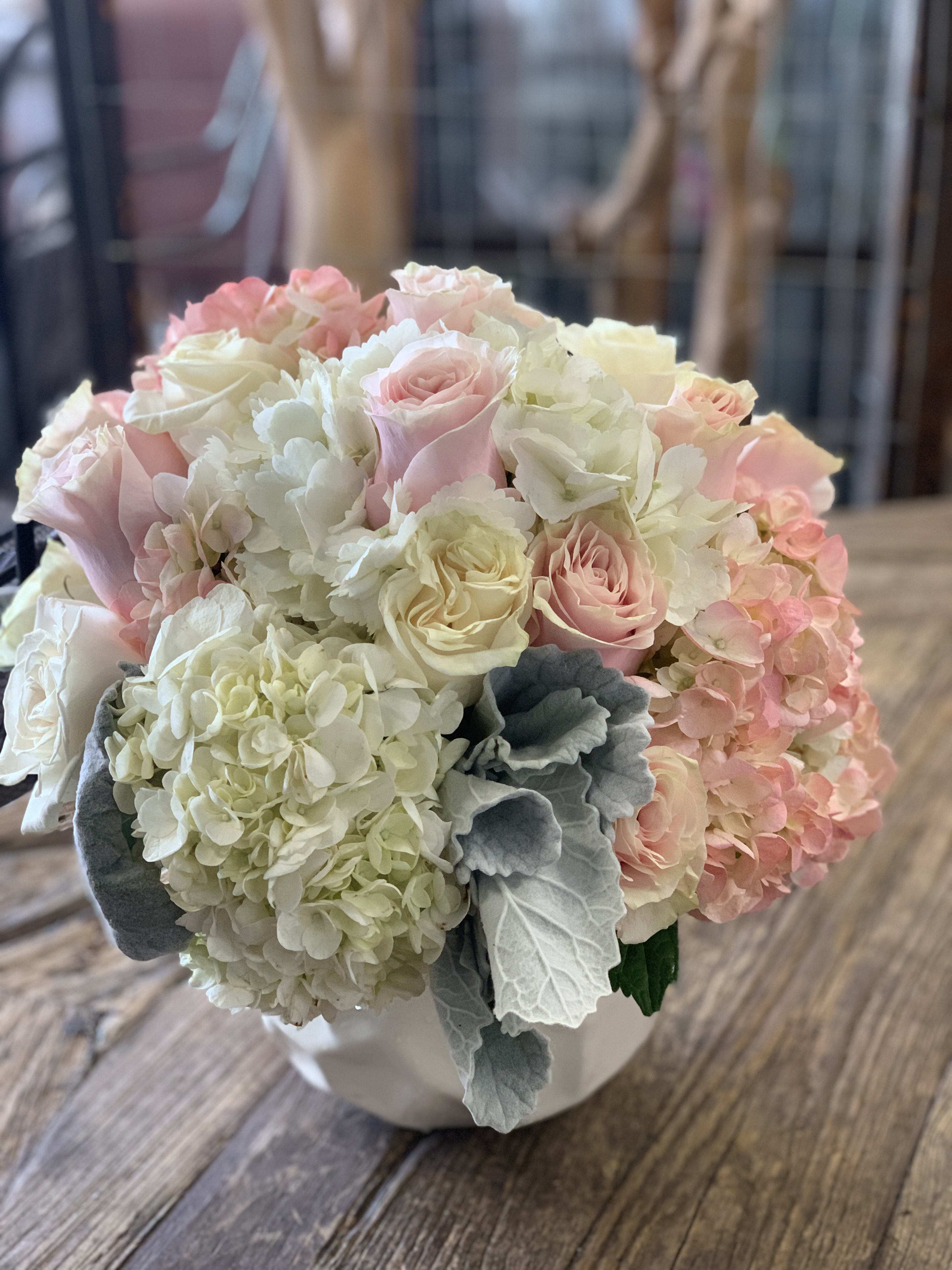 Bouquet of pale pink roses and white hydrangeas in a white container