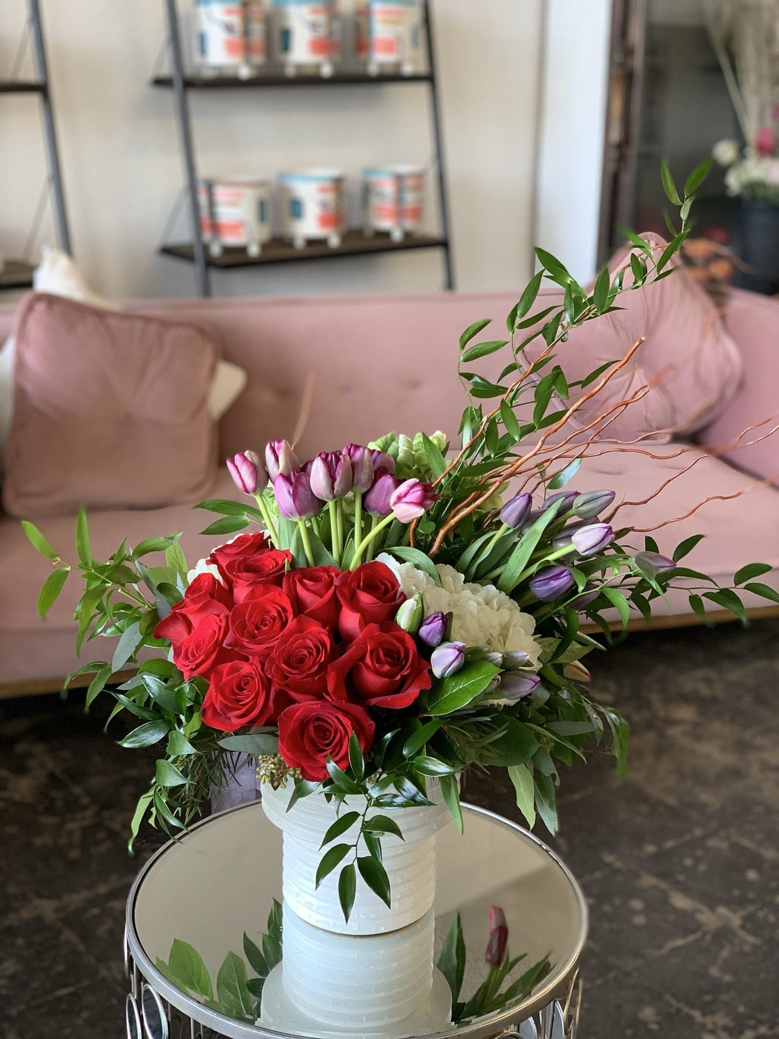 Bouquet of red roses and purple tulips in a white vase