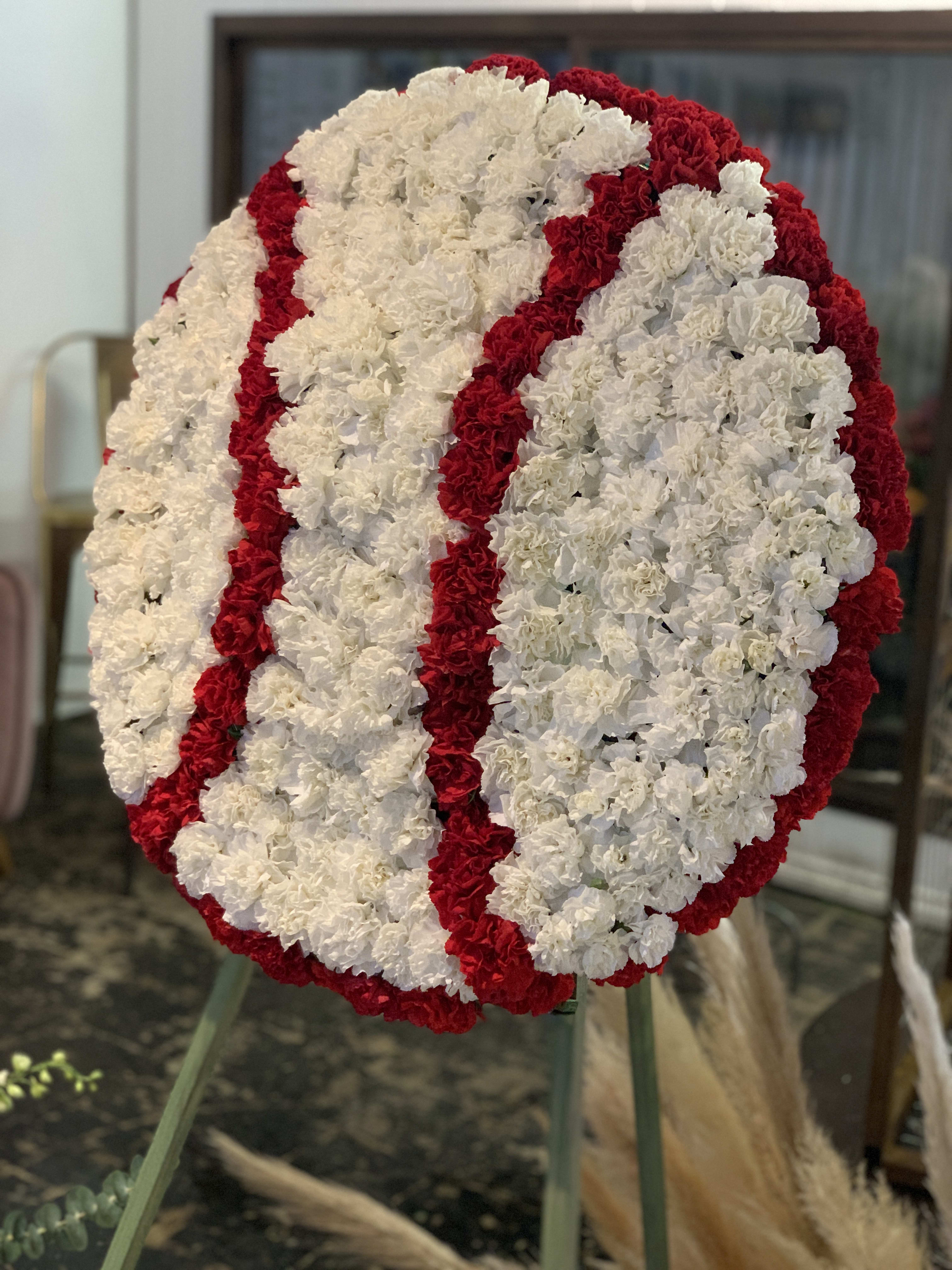Large circular floral wreath of white and red carnations on an easel