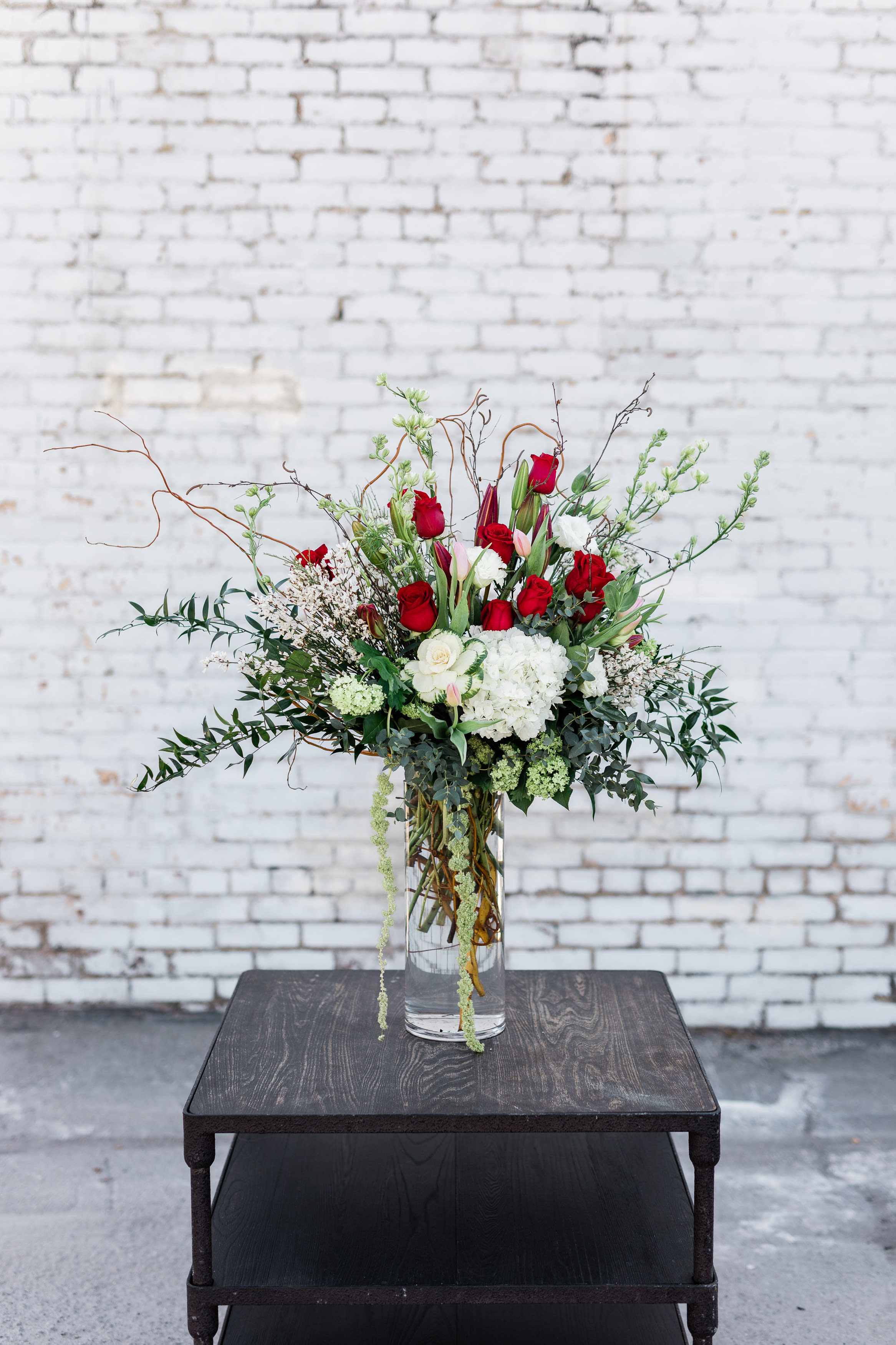 Tall bouquet of red and white flowers in a clear glass vase