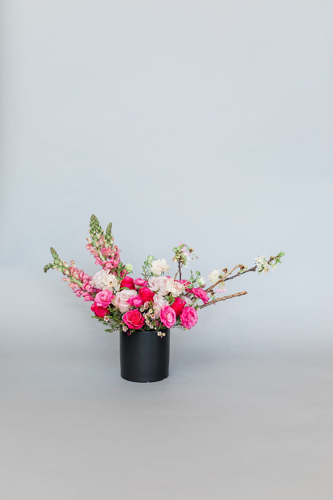 Pink and white floral arrangement in a black cylindrical vase