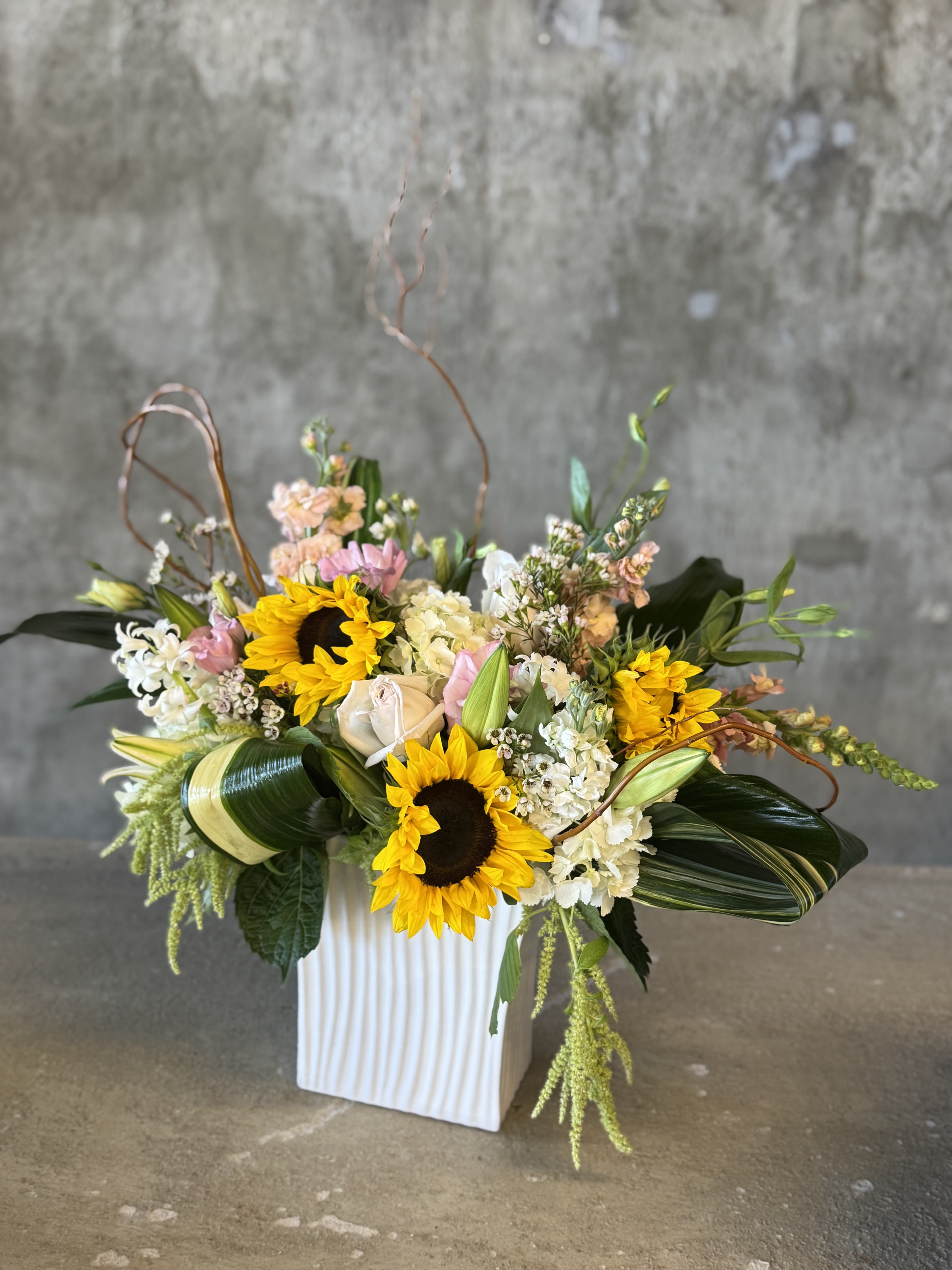 Mixed floral arrangement with sunflowers and roses in a white vase