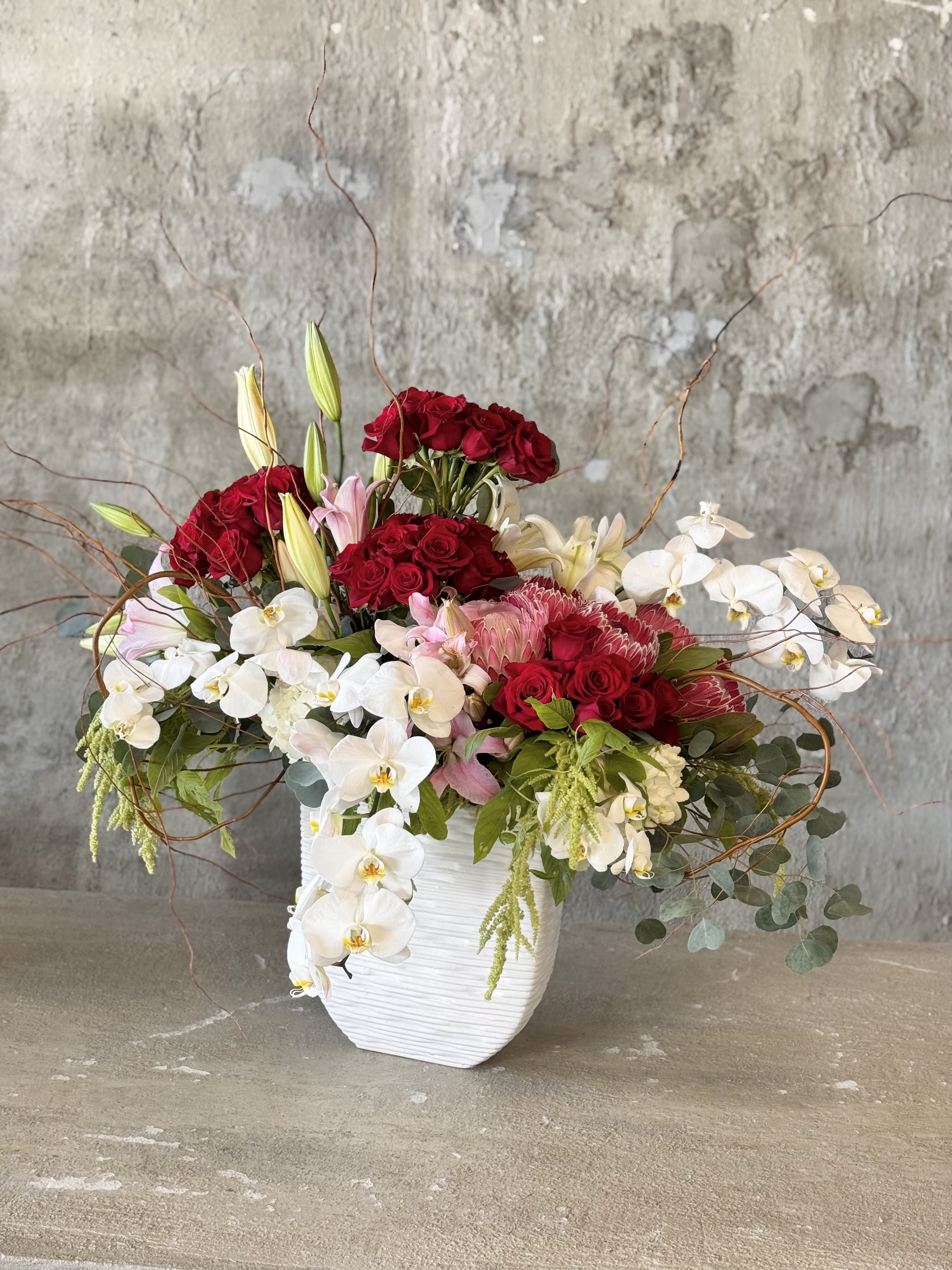 Red roses and white orchids arranged in a white vase