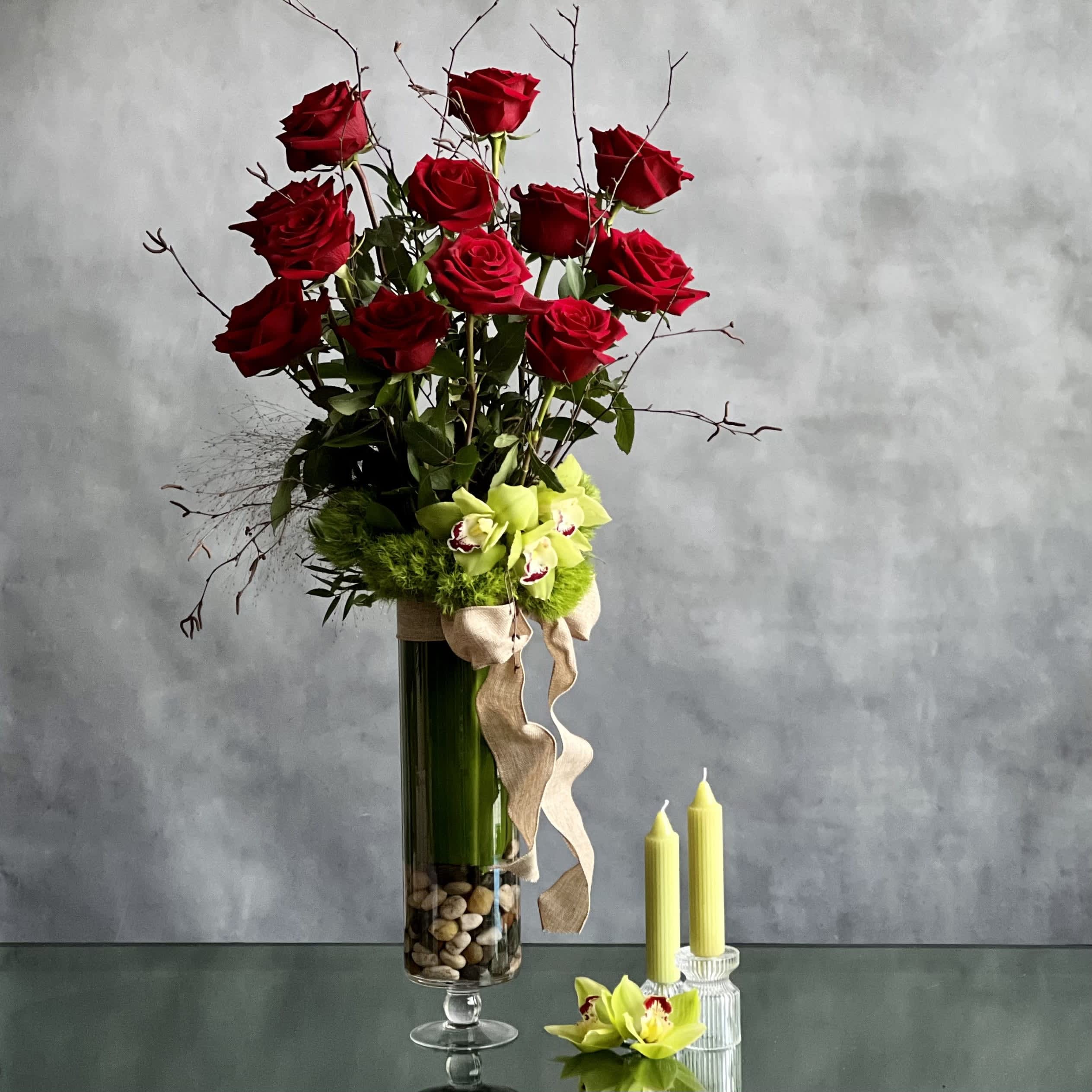 Tall bouquet of red roses and green orchids in a glass vase