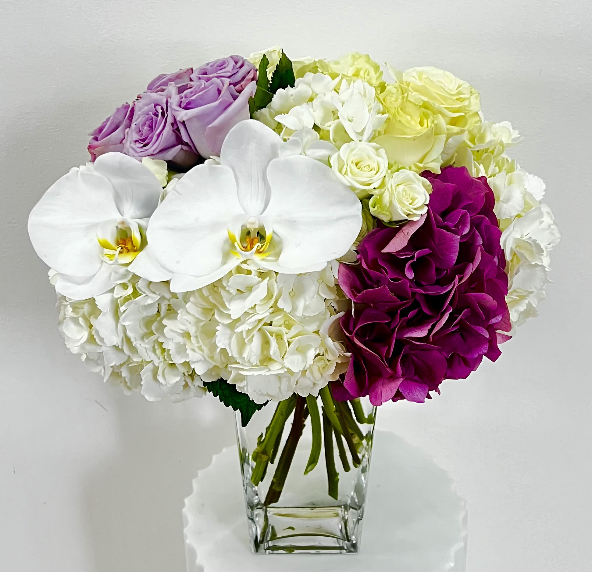 Bouquet of white orchids, hydrangeas, and roses in a clear glass vase