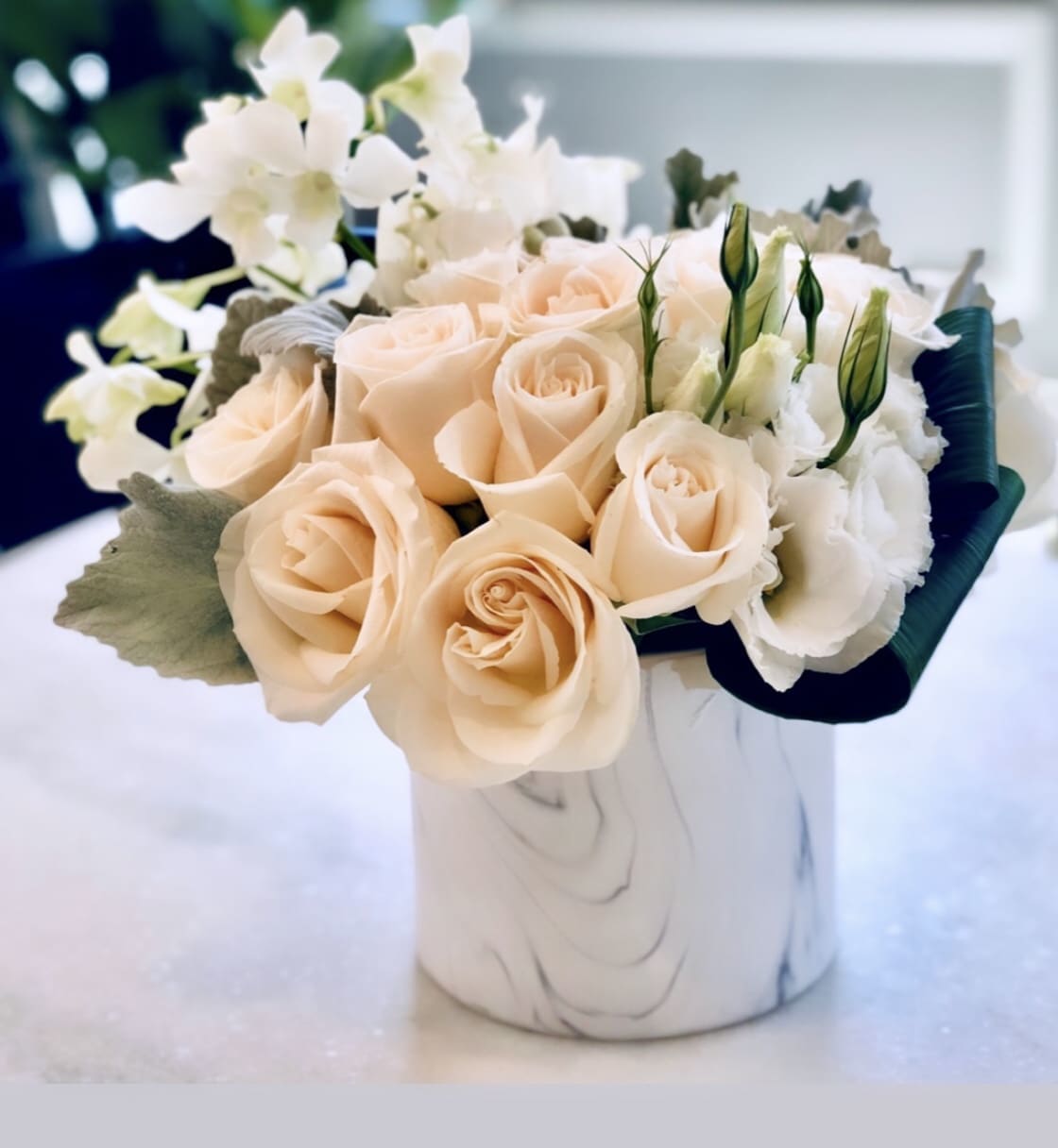 Peach roses and white flowers arranged in a white vase