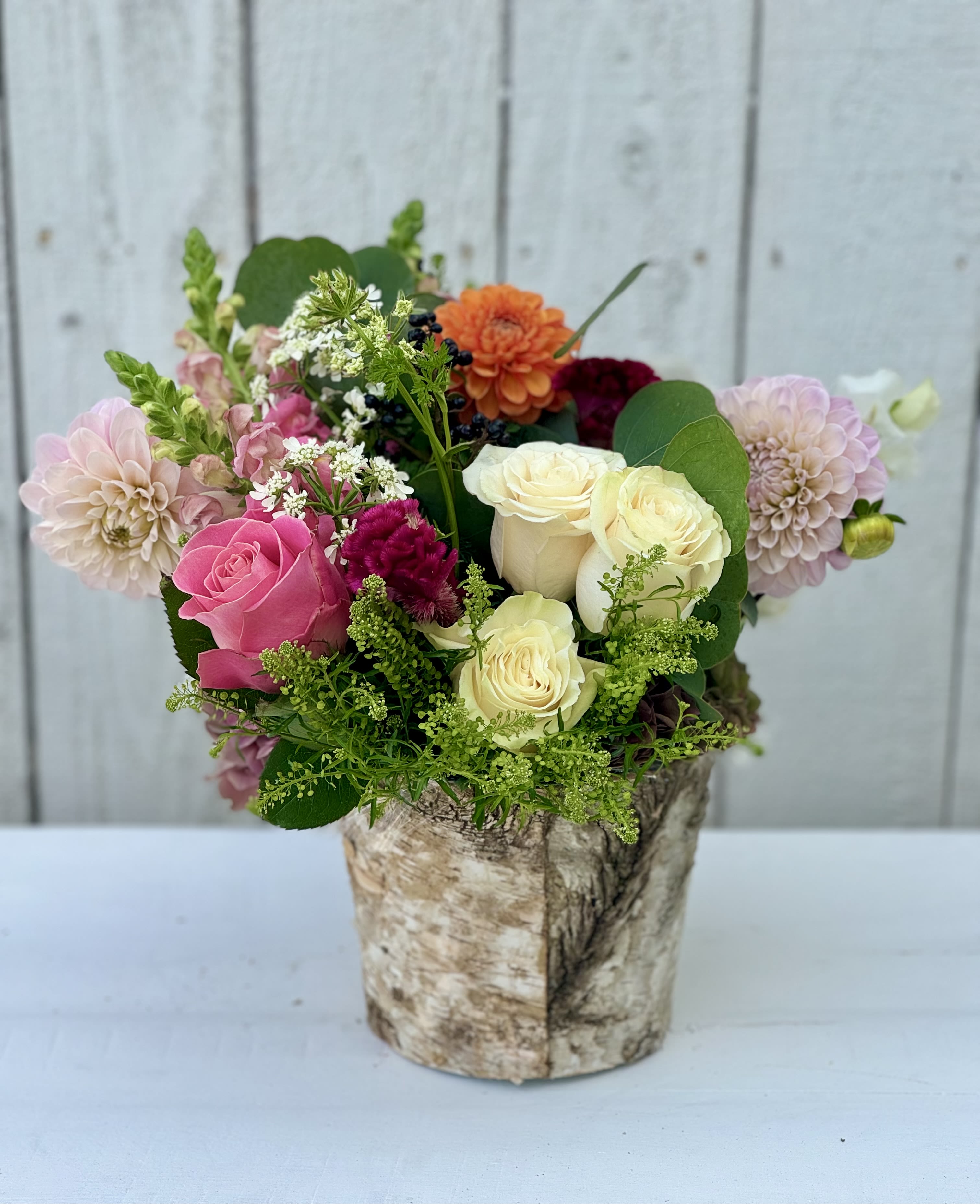 Mixed bouquet of roses and dahlias in a birch-style container