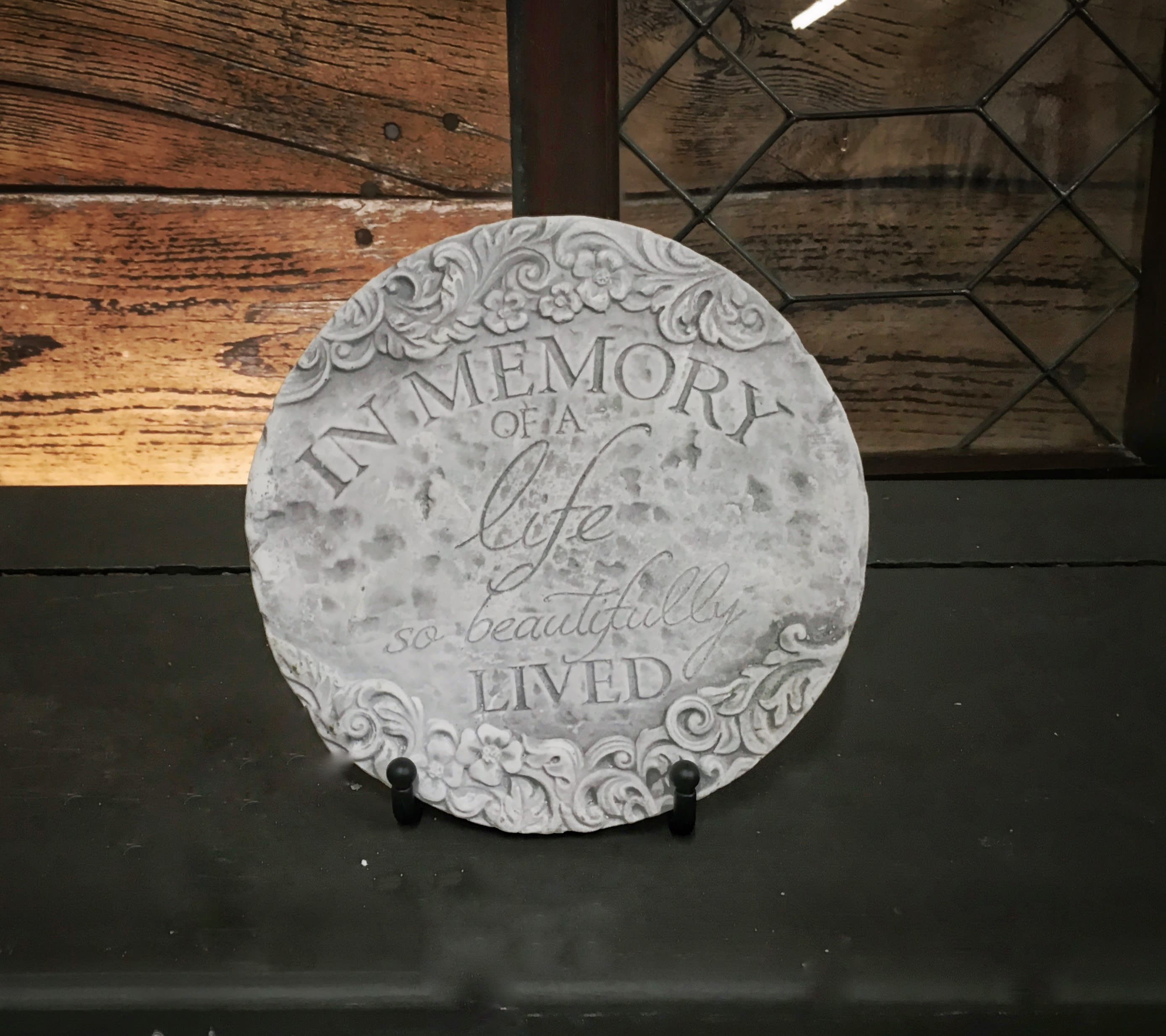 Round memorial plaque with the words In Memory of a life so beautifully lived