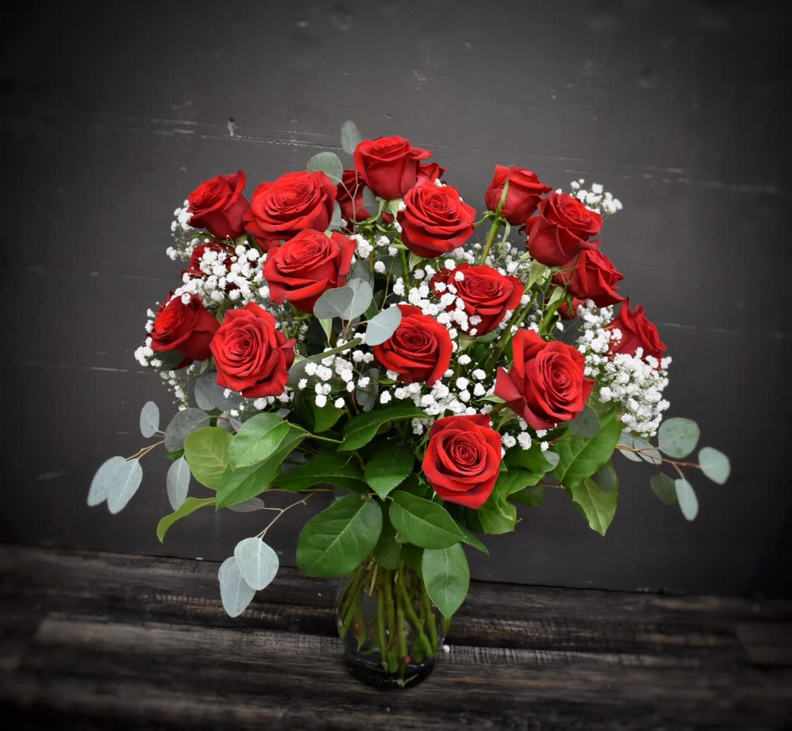 Double Dozen -  24 red roses designed in a clear glass vase with assorted green foliages. WOW!