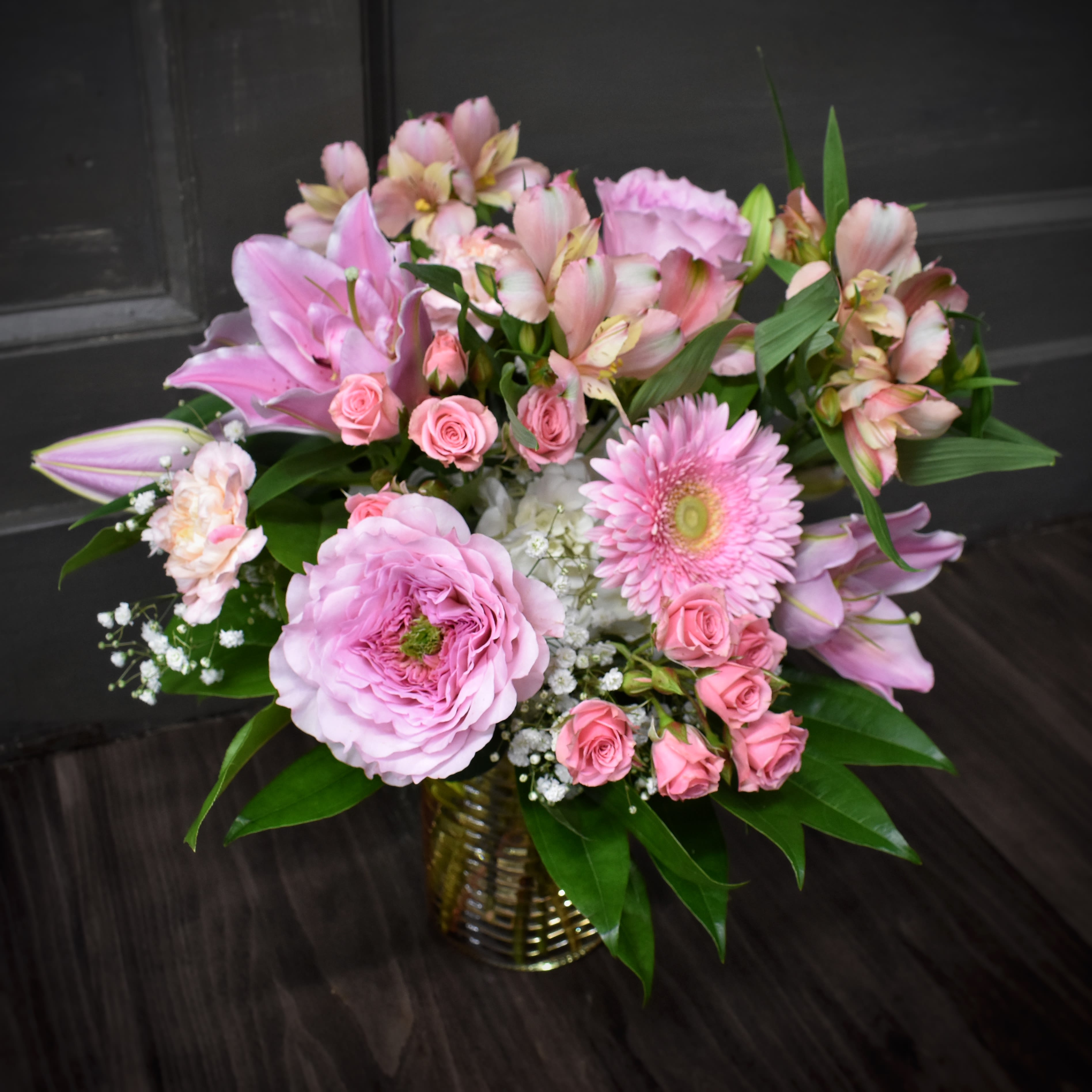 Pink mixed flower arrangement in a gold vase