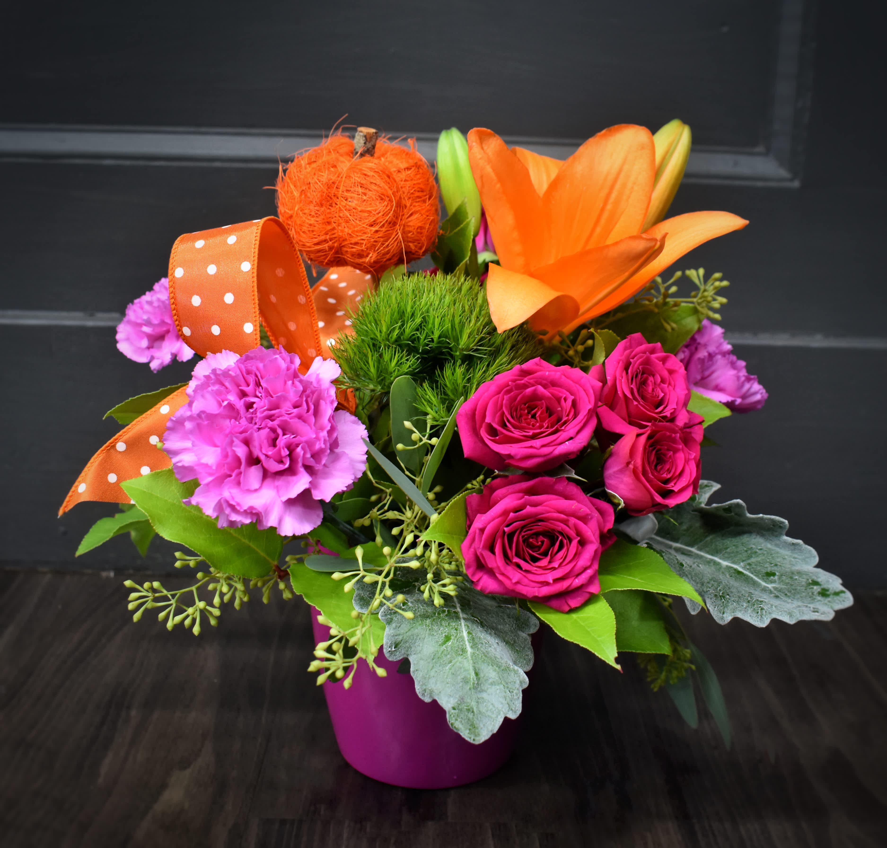 Bright mixed bouquet in a magenta pot with orange lilies and pink roses