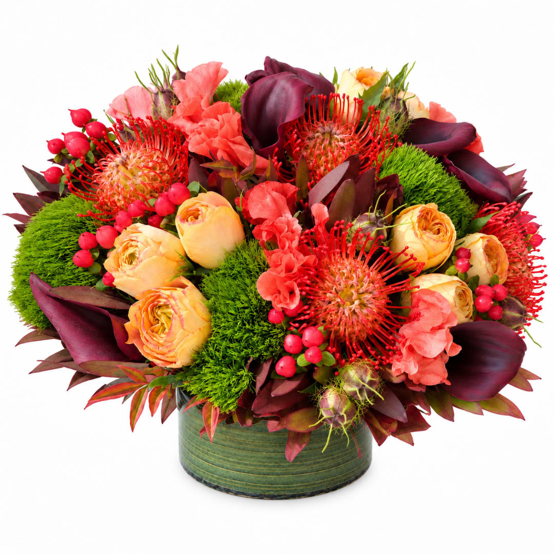 Bright mixed bouquet in a green round vase with red and peach blooms