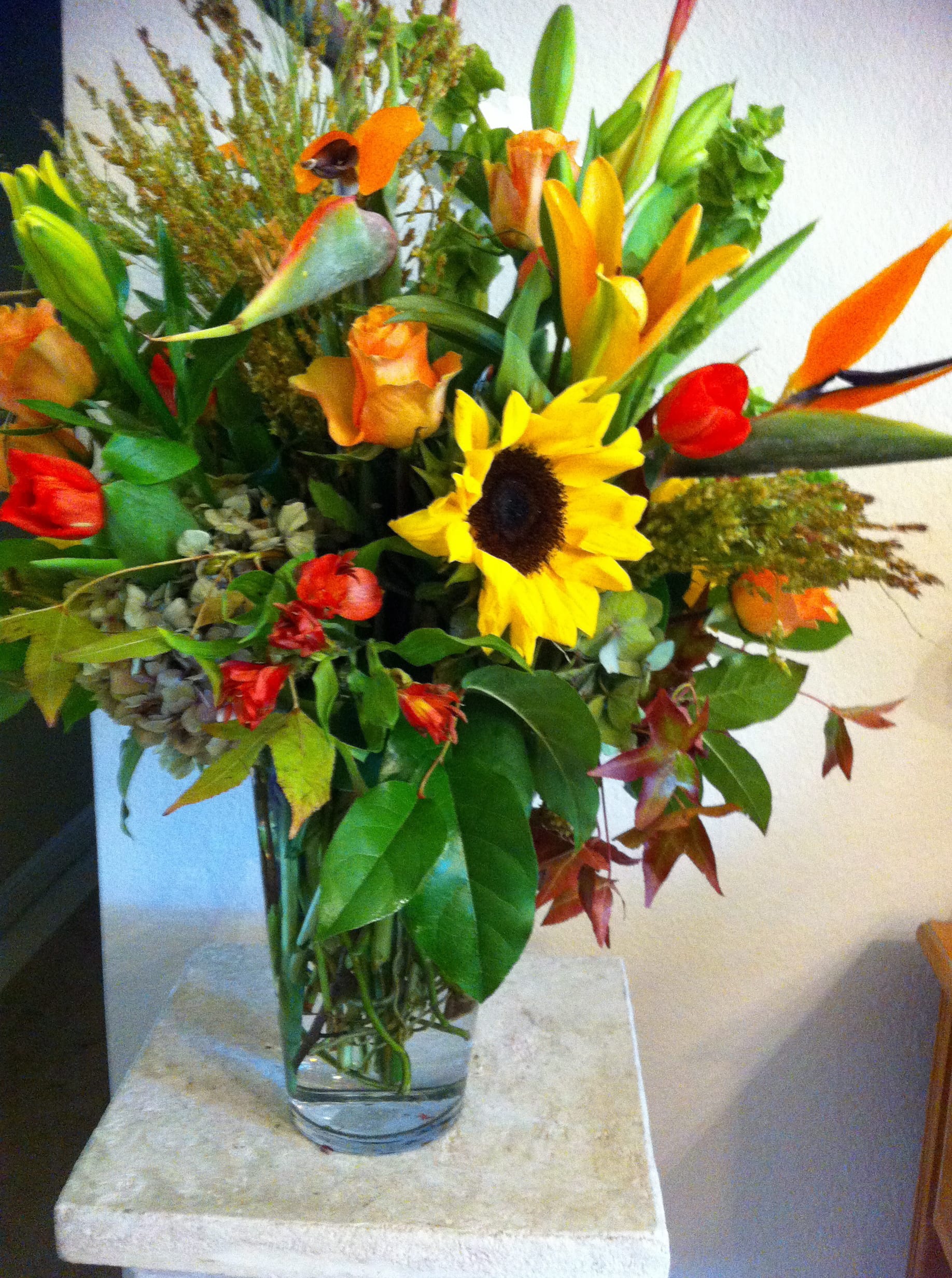 Mixed bouquet with sunflowers, lilies, and orange roses in a glass vase